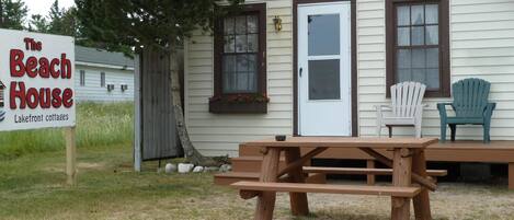 Una mesa de picnic de madera frente a una cabaña con un letrero que dice "The Beach House Lakefront cottages".