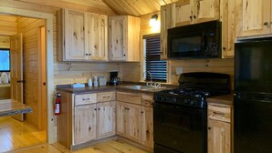 Una cocina con armarios de madera, estufa, microondas y lavaplatos.