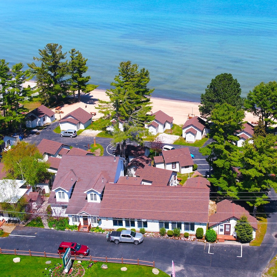 An aerial view of a coastal residential area with houses, a beach, and a road.
