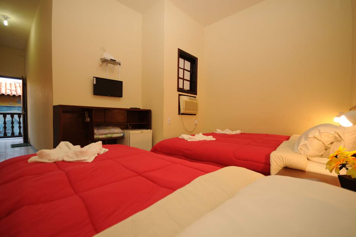 Ein Hotelzimmer mit zwei Betten, einem Fernseher, einer Klimaanlage und einem Balkon mit Geländer.