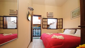 Une chambre d’hôtel avec deux lits, un grand miroir, la climatisation et une vue sur le balcon extérieur.