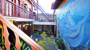Une cour agrémentée d’une fresque murale, d’un escalier et d’un espace aménagé avec des tables et des chaises.
