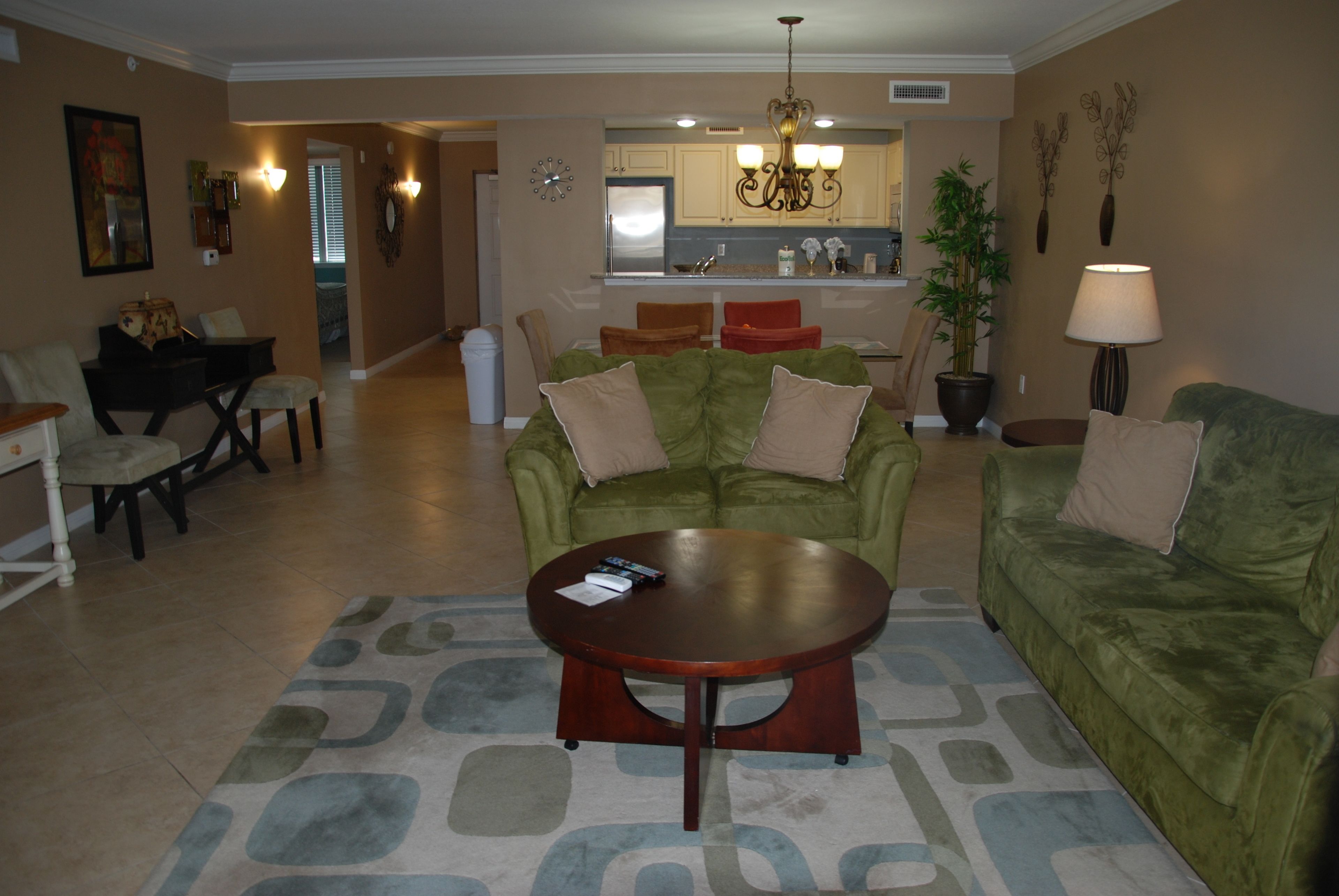 A living room with a green sofa, a wooden coffee table, and a patterned rug.