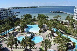Un complexe hôtelier doté d’une grande piscine centrale, de palmiers et offrant une vue sur la mer.