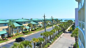 A row of hotel buildings with green roofs, a parking lot, and palm trees. - Destin West Vacations (Fort Walton Beach)