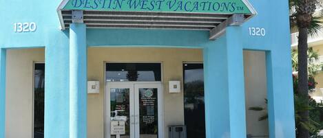 Exterior de Destiny West Vacations, con fachada color turquesa, un logo de tortuga y el número 1320.