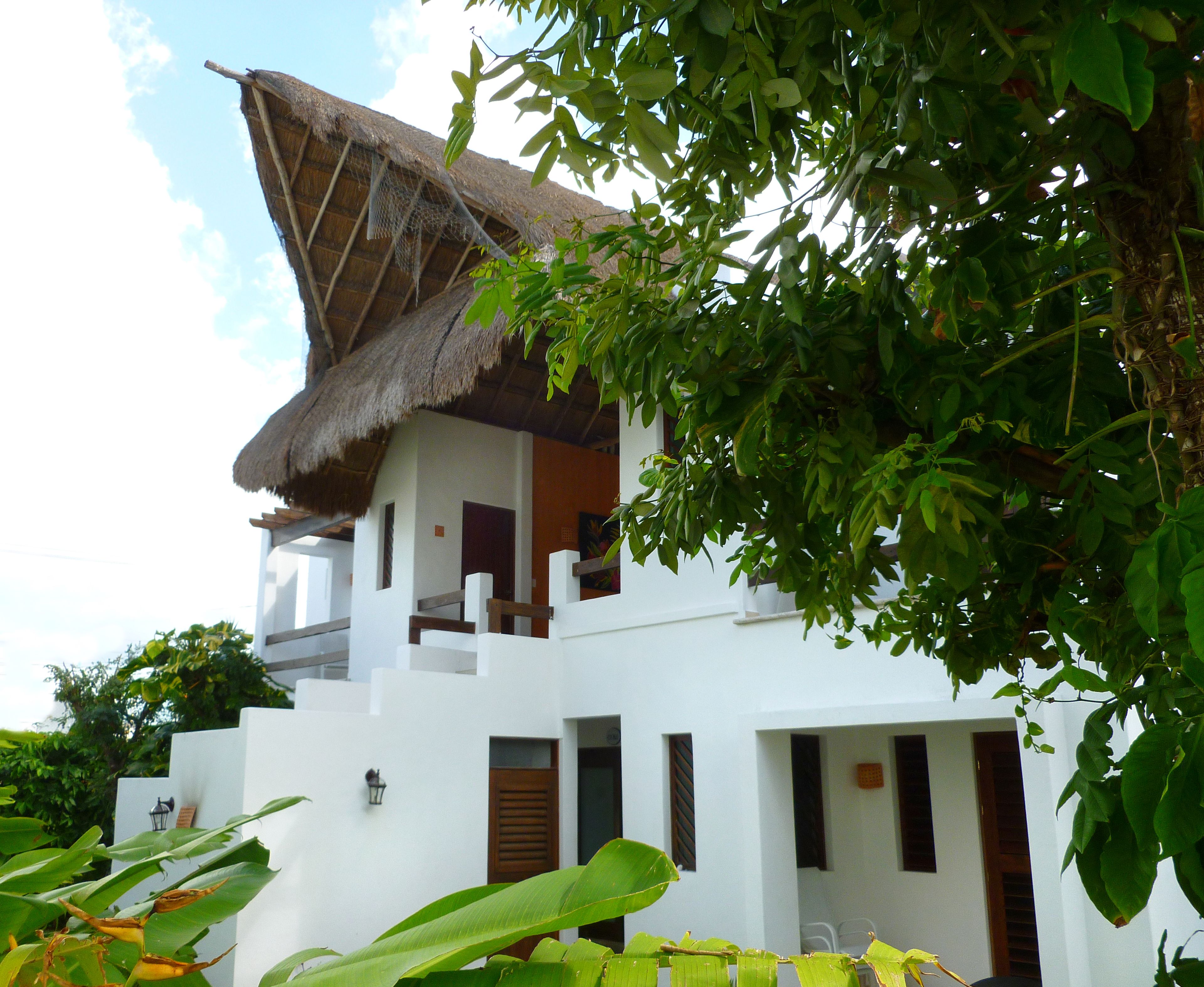 A white building with a thatched roof and multiple balconies.