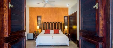 A hotel room with a large bed, wooden panel walls, a ceiling fan, and two bedside lamps.