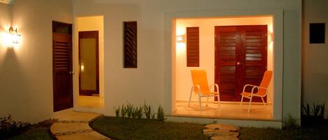 A modern house with a stone pathway leading to a wooden door and a set of double doors with an orange chair outside.