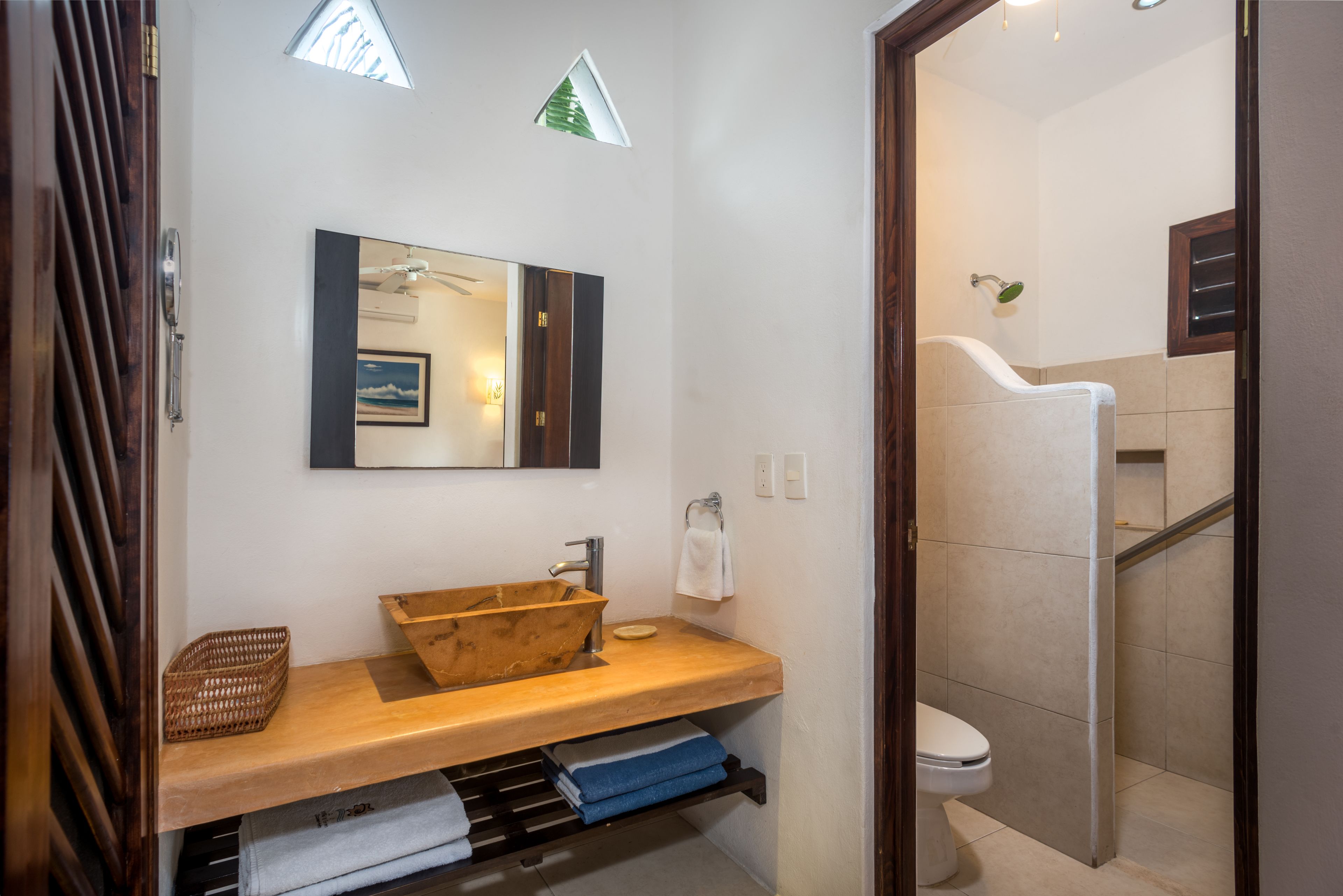 Une salle de bain avec un meuble-lavabo en bois, un grand miroir, un porte-serviettes et un espace douche.