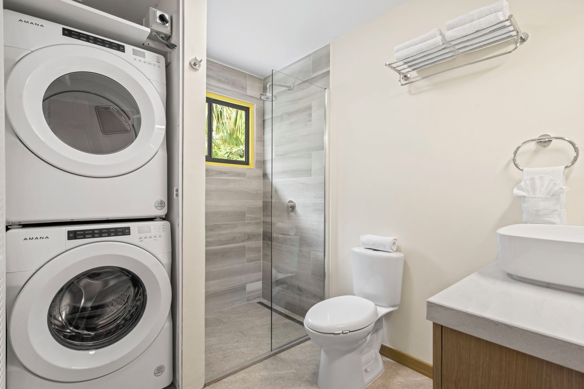 Un baño moderno con cabina de ducha de vidrio, inodoro y lavadora.