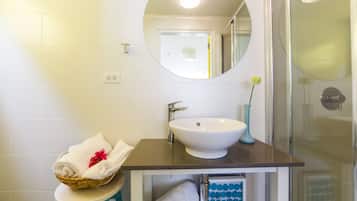 A bathroom with a white sink, a mirror, and a shower.