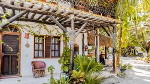 A traditional house with a wooden porch, potted plants, and a thatched roof.