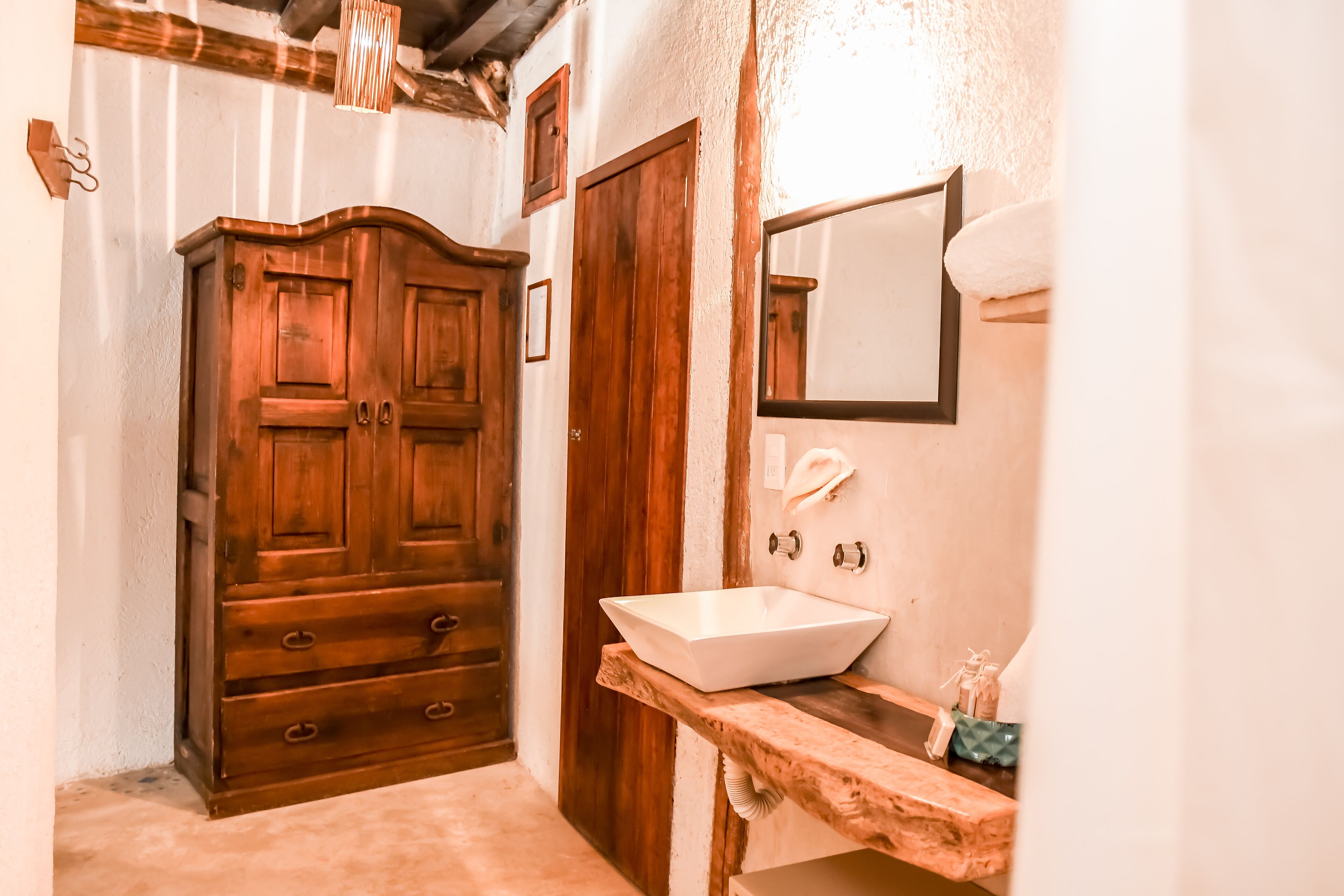 A bathroom with a wooden wardrobe, a sink, and a mirror.