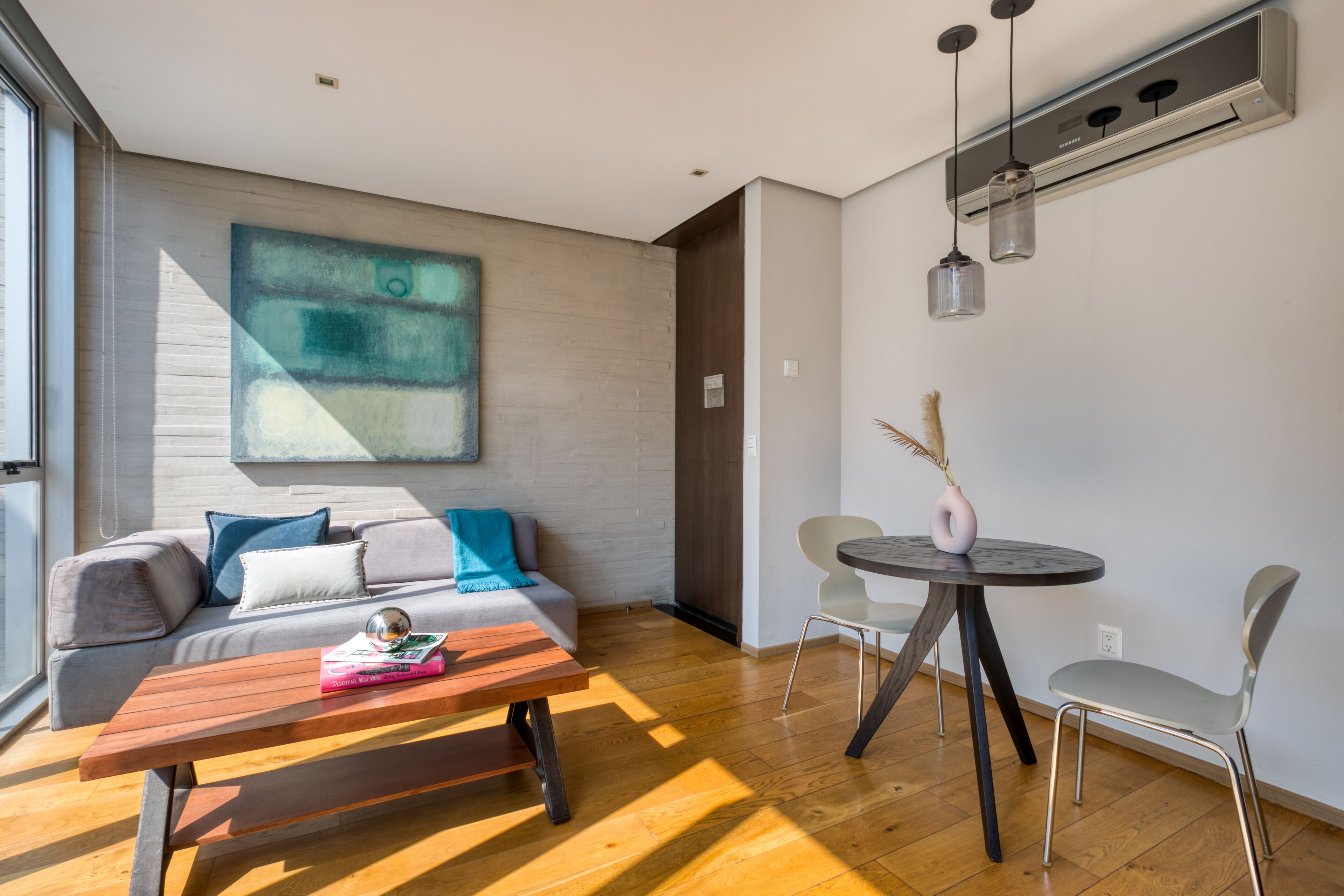 A modern living room with a sofa, a coffee table, and a dining area with a table and chairs.