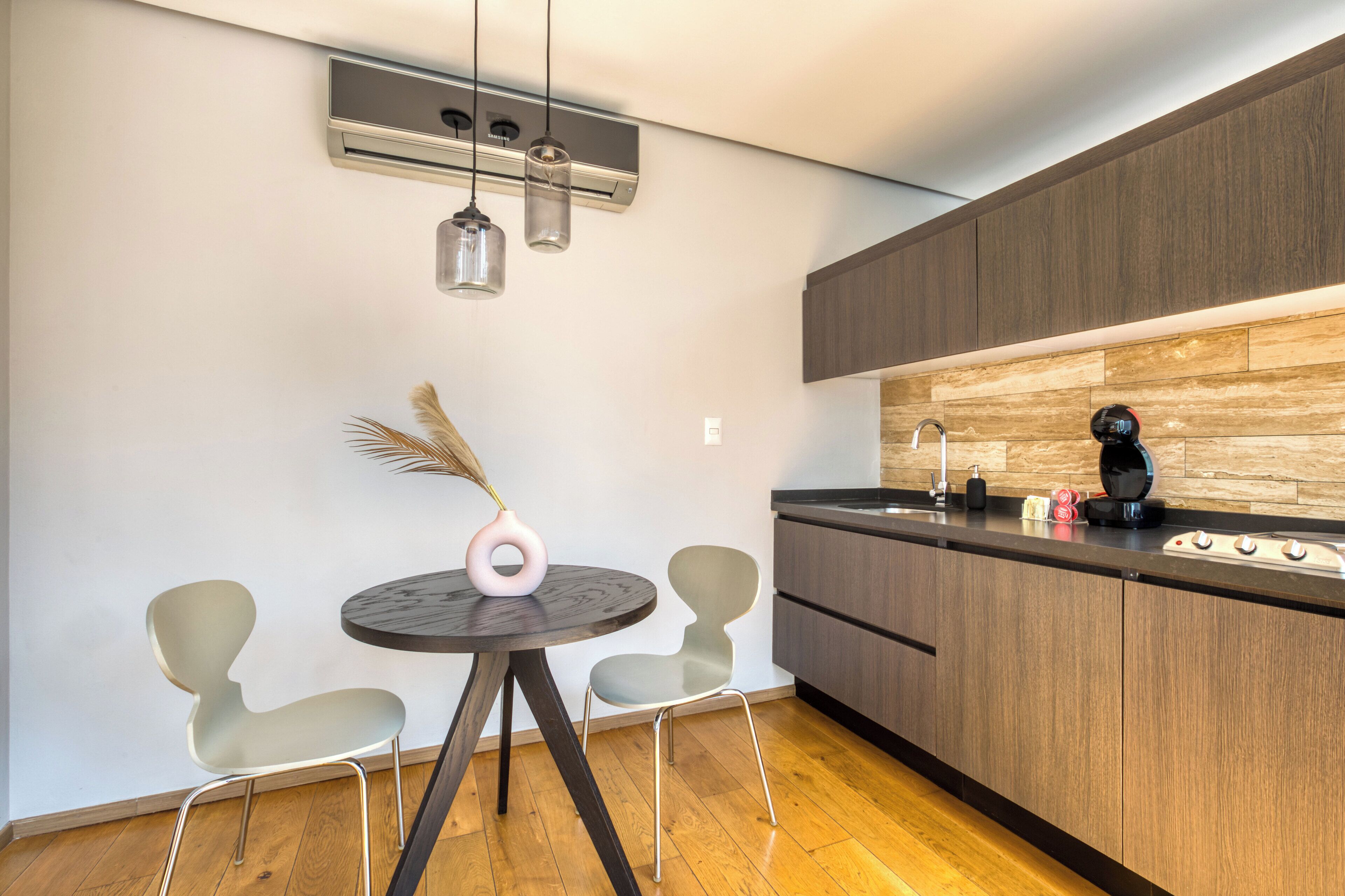 Una cocina moderna con armarios de madera, encimera negra y una mesa redonda con dos sillas.