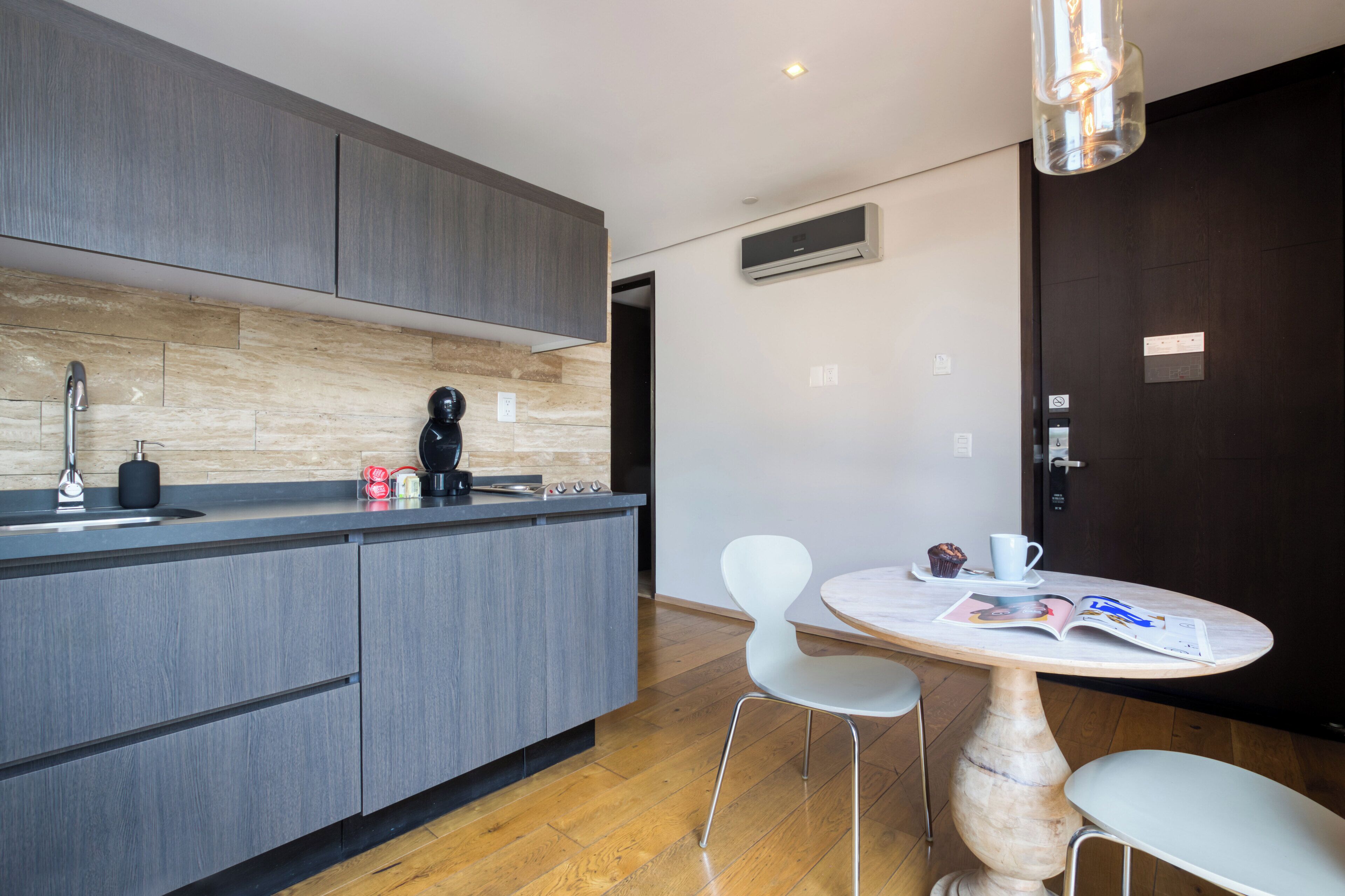 A modern kitchen with grey cabinets, a wooden backsplash, and a dining area with a round table and two chairs.