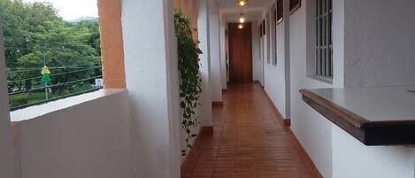 A corridor with tiled flooring, white walls, and hanging lights.