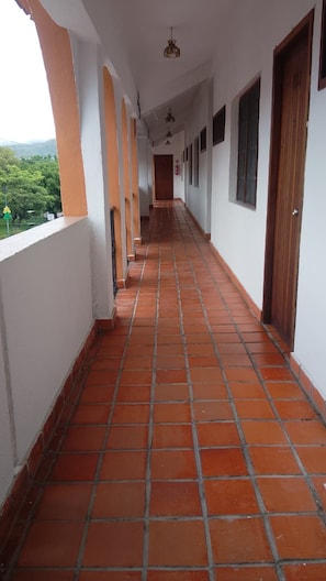 A corridor with a tiled floor, white walls, and wooden doors.