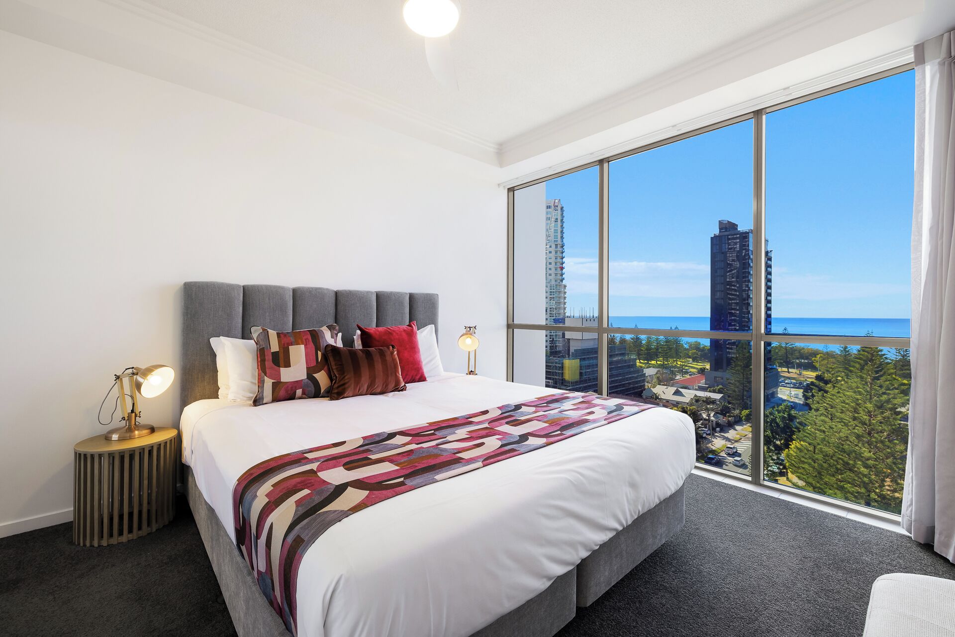 A modern hotel room with a large bed, a view of the city, and a balcony.