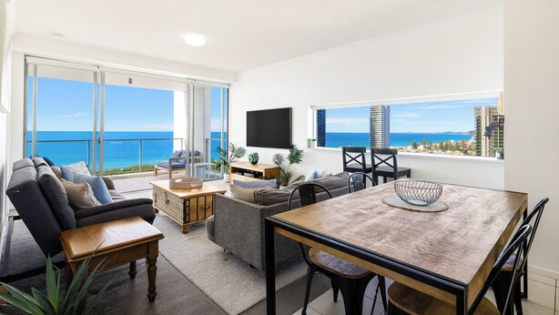 Amplia sala de estar con balcón y vistas al mar, una mesa de comedor y asientos cómodos.