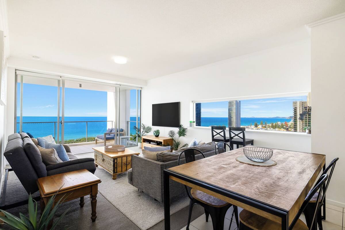 Amplia sala de estar con balcón y vistas al mar, una mesa de comedor y asientos cómodos.
