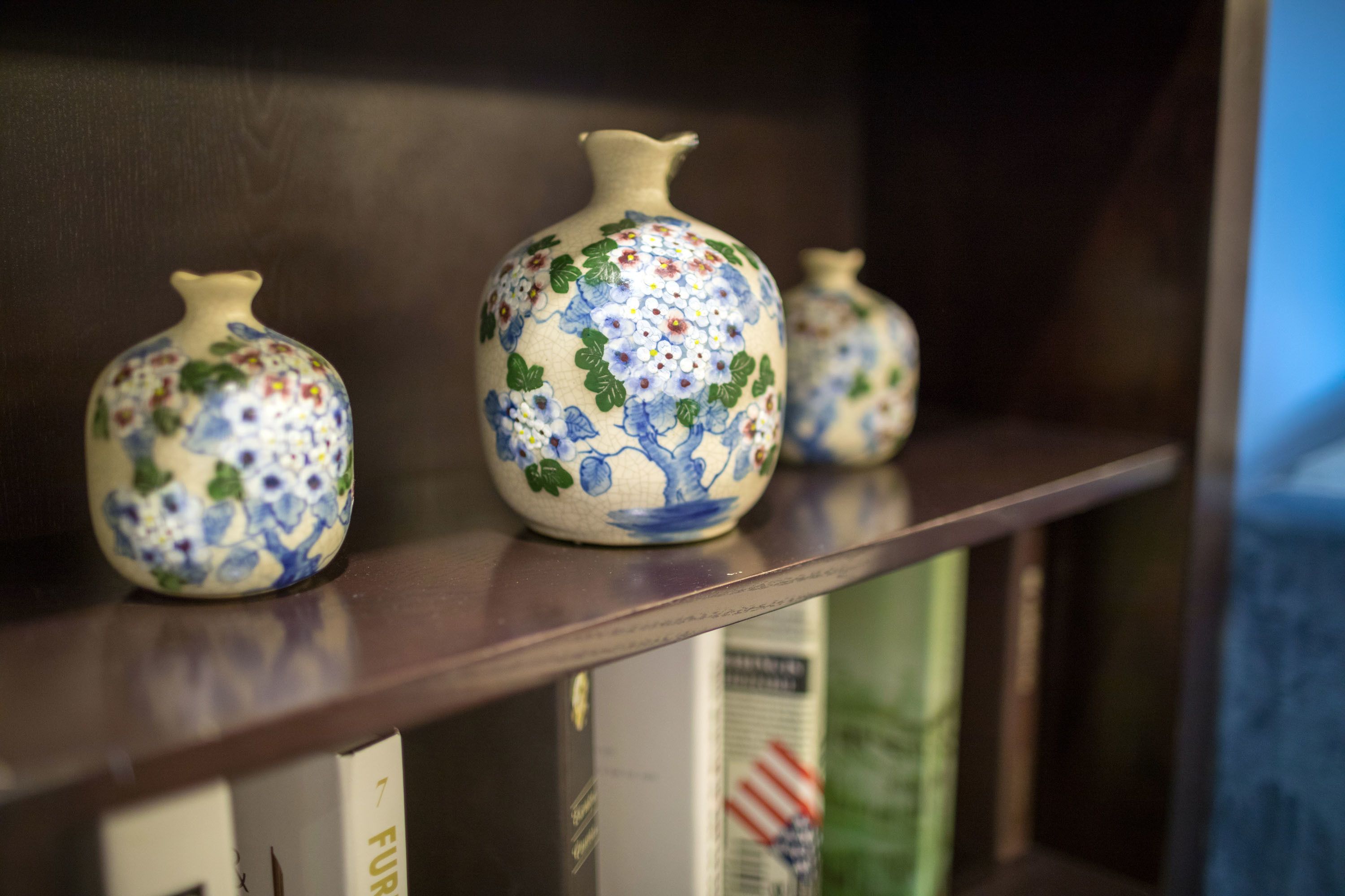 Three ceramic vases with floral patterns on a shelf.