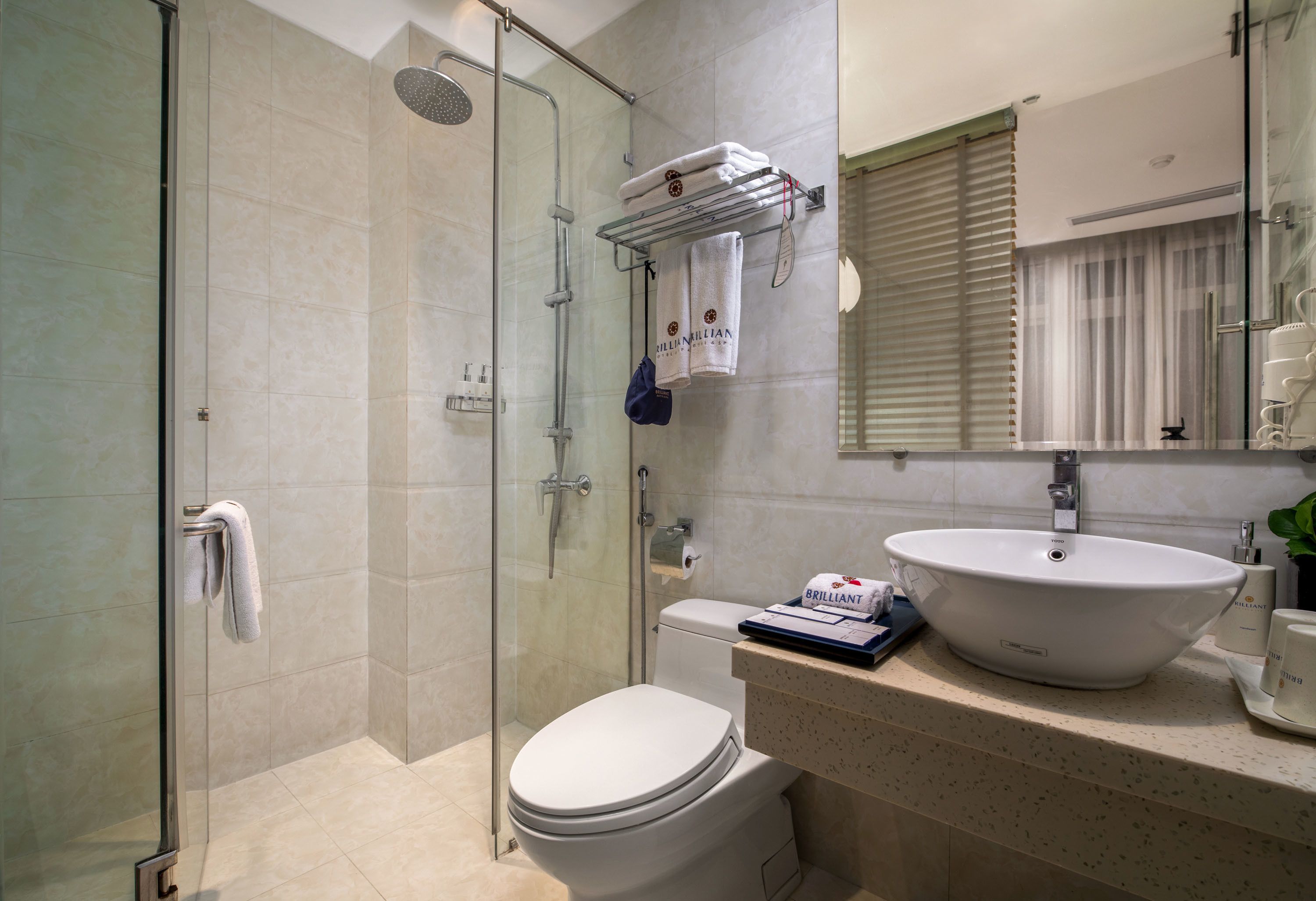 A modern bathroom with a glass-enclosed shower, a white toilet, and a sink with a mirror above.