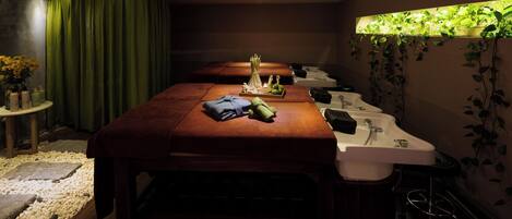Una stanza spa con un lettino da massaggio, due lavabi, un tavolino con articoli da toilette e una tenda verde.