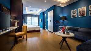 Een moderne hotelkamer met een bed, een bureau, een stoel, een bank, een tafel en een televisie.