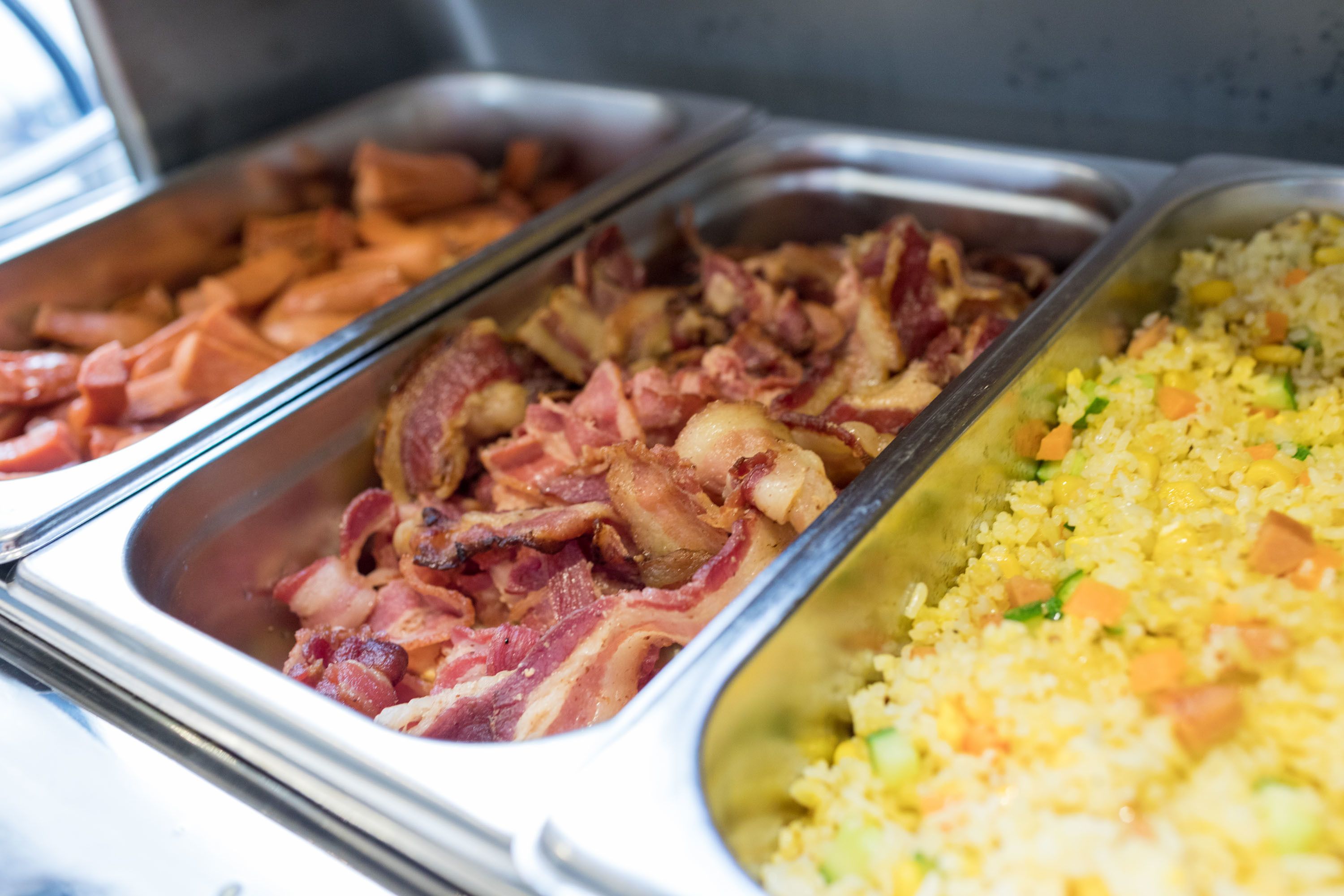 A buffet with various food options including bacon, fried rice, and other dishes.
