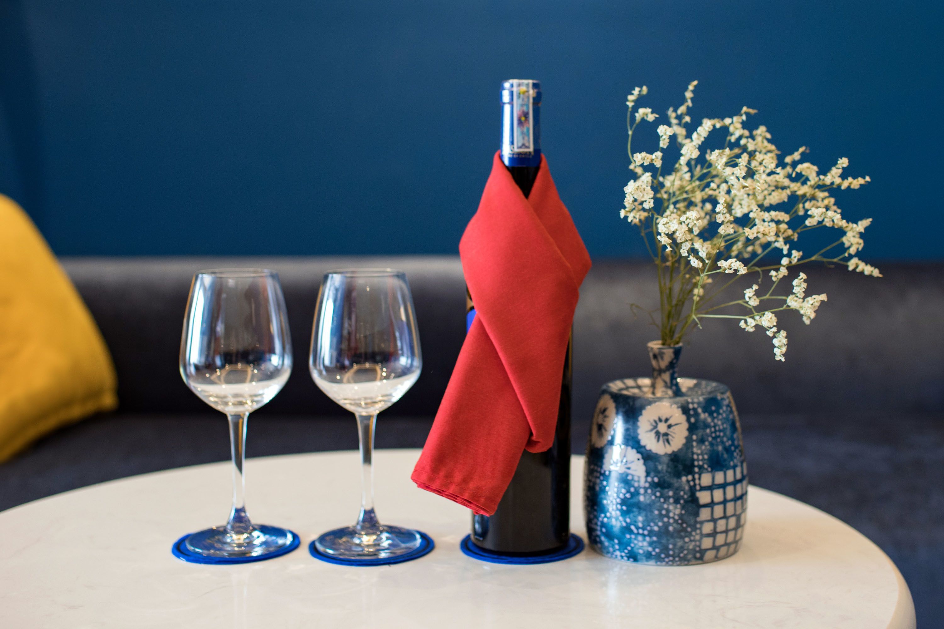 A table with two wine glasses, a bottle of wine, a red napkin, and a vase with flowers.
