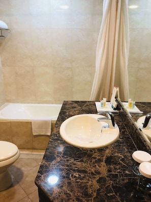 Une salle de bain avec un lavabo en marbre, une baignoire et des toilettes.