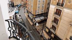 Un immeuble à plusieurs étages doté de balcons, une rue en contrebas et un tramway.