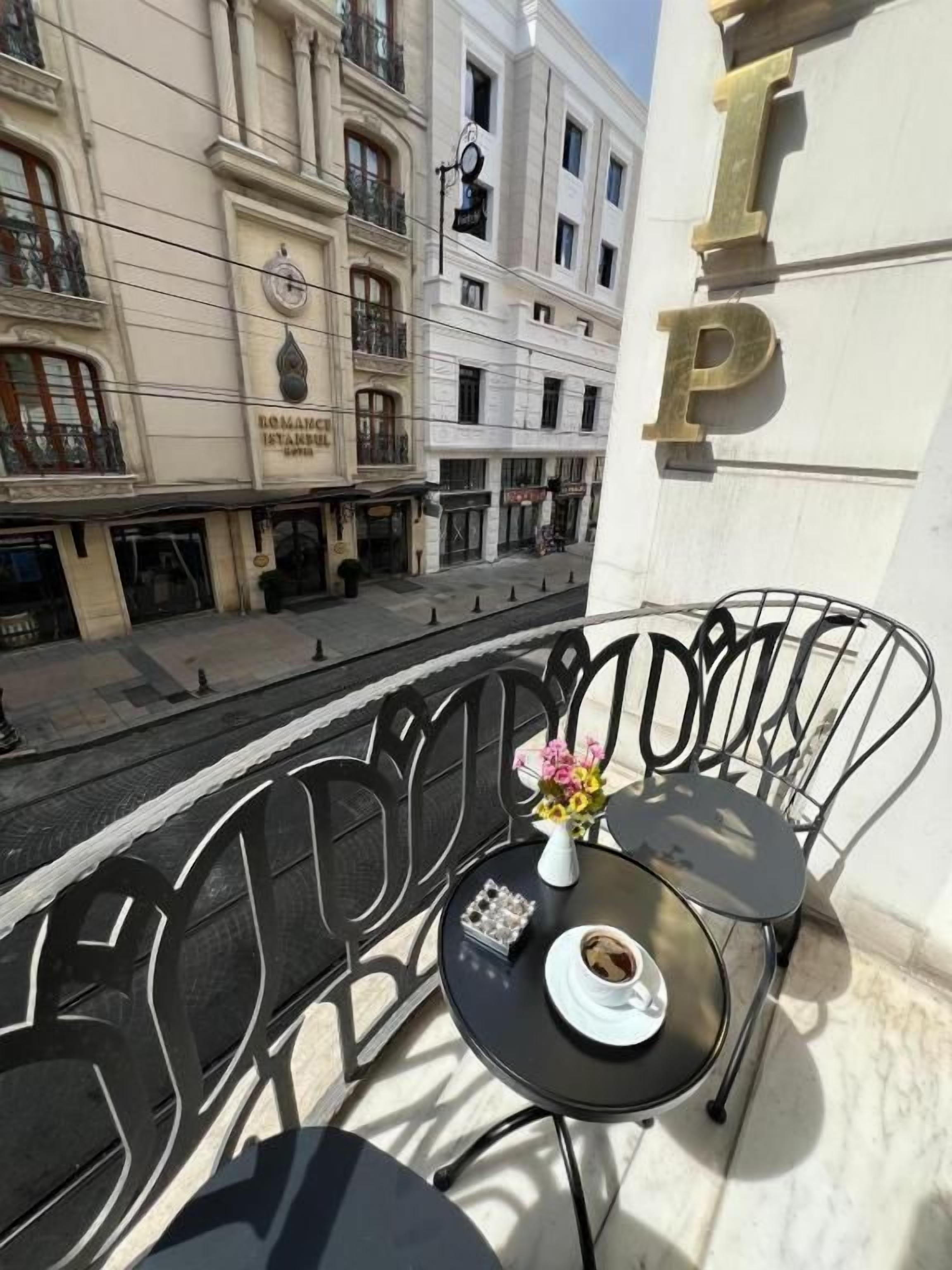 A balcony with a table and chairs, overlooking a street with buildings.