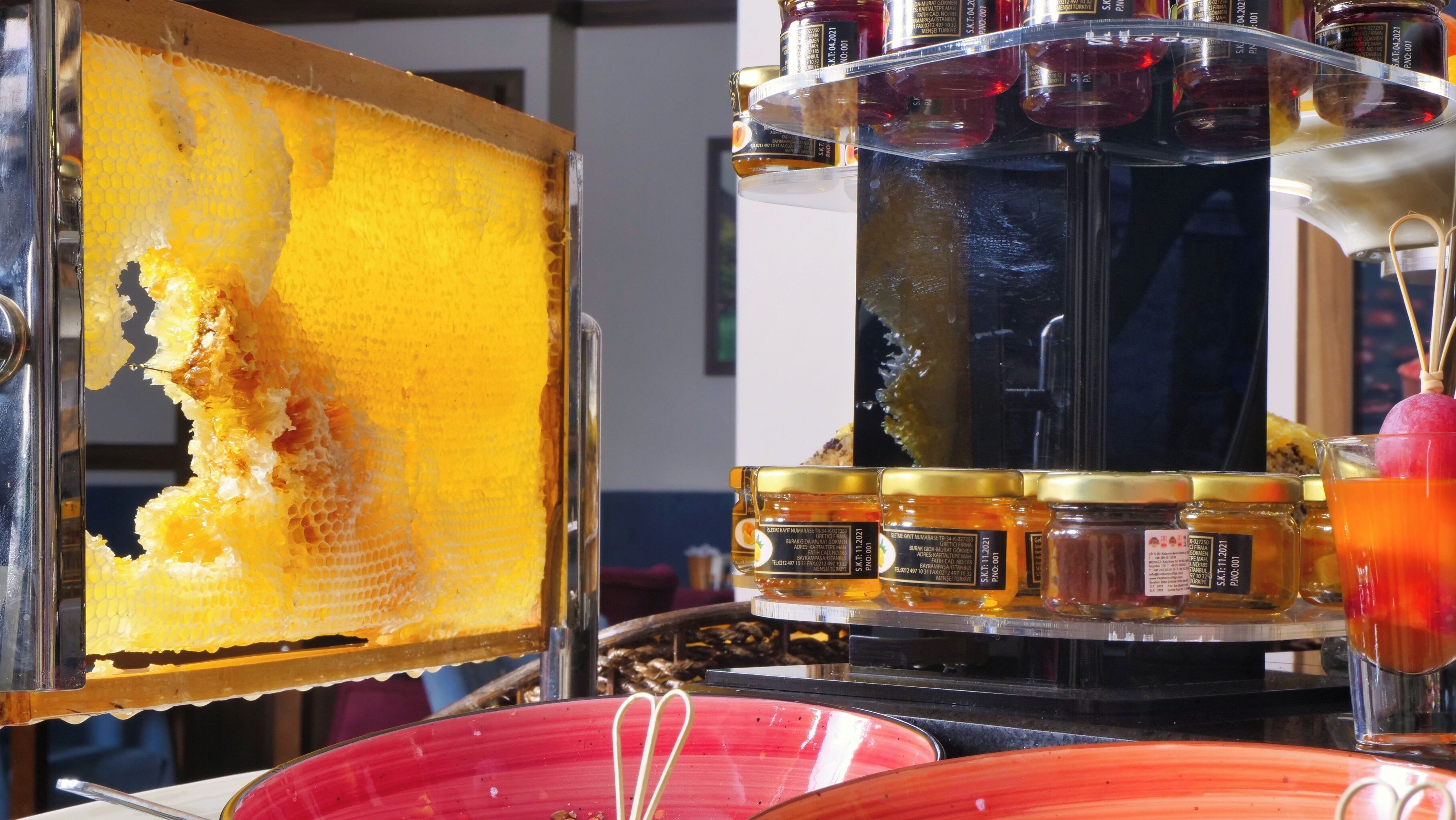 A honeycomb with a honey dipper and jars of honey on a display.
