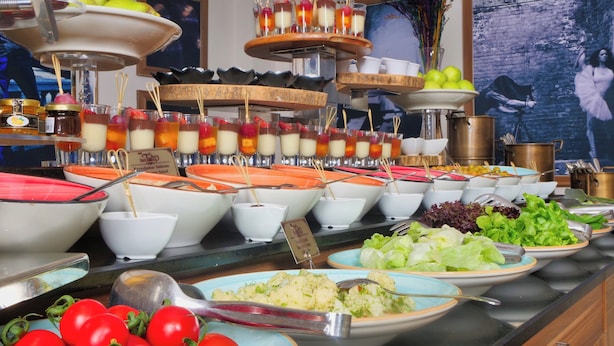 Un buffet proposant une variété de plats, notamment des salades, des fruits et des desserts.