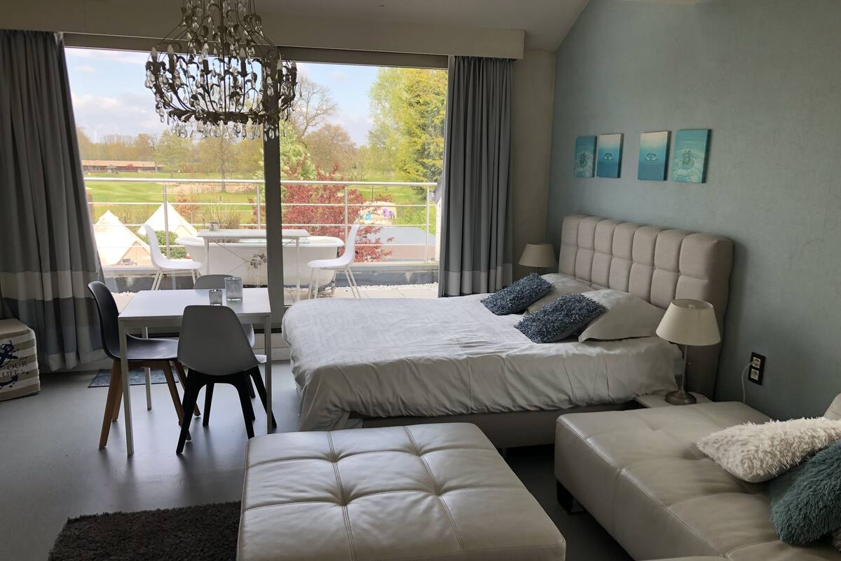 Un dormitorio moderno con una cama grande, un sofá, una mesa de comedor y vistas al exterior.