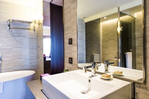 A modern bathroom with a large sink, two faucets, and a mirror.