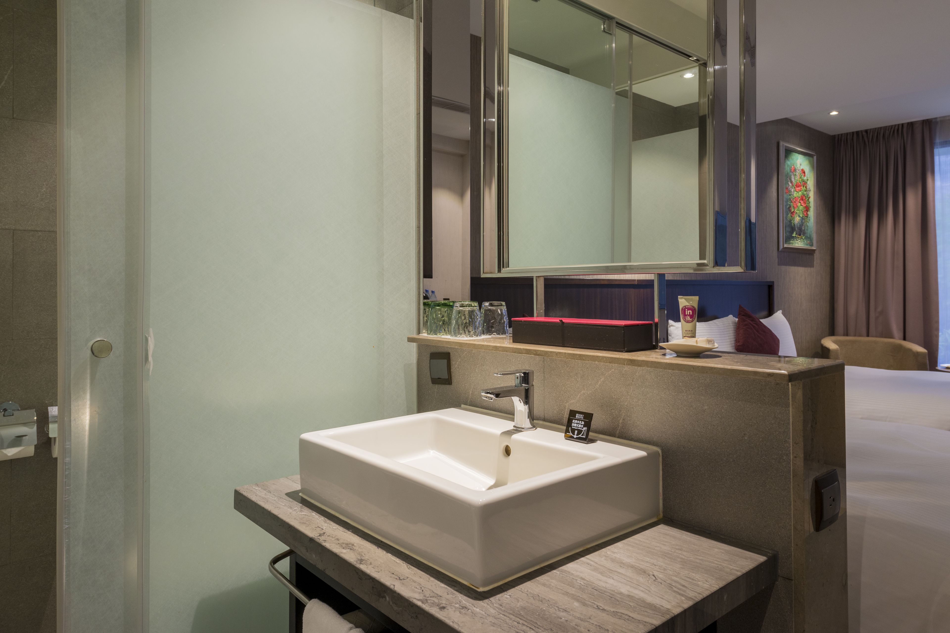 A modern bathroom with a large mirror, a rectangular sink, and a countertop with toiletries.