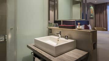A modern bathroom with a large mirror, a rectangular sink, and a countertop with toiletries.