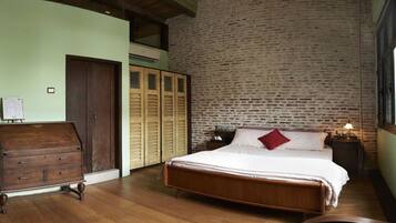 A bedroom with a wooden bed, a dresser, and a brick wall.