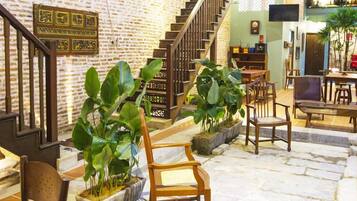 Un hall d’entrée spacieux avec un escalier, des chaises en bois et des plantes en pot.