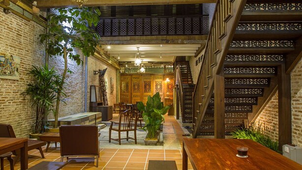 A cozy indoor space with wooden tables and chairs, a staircase, and decorative wooden panels.