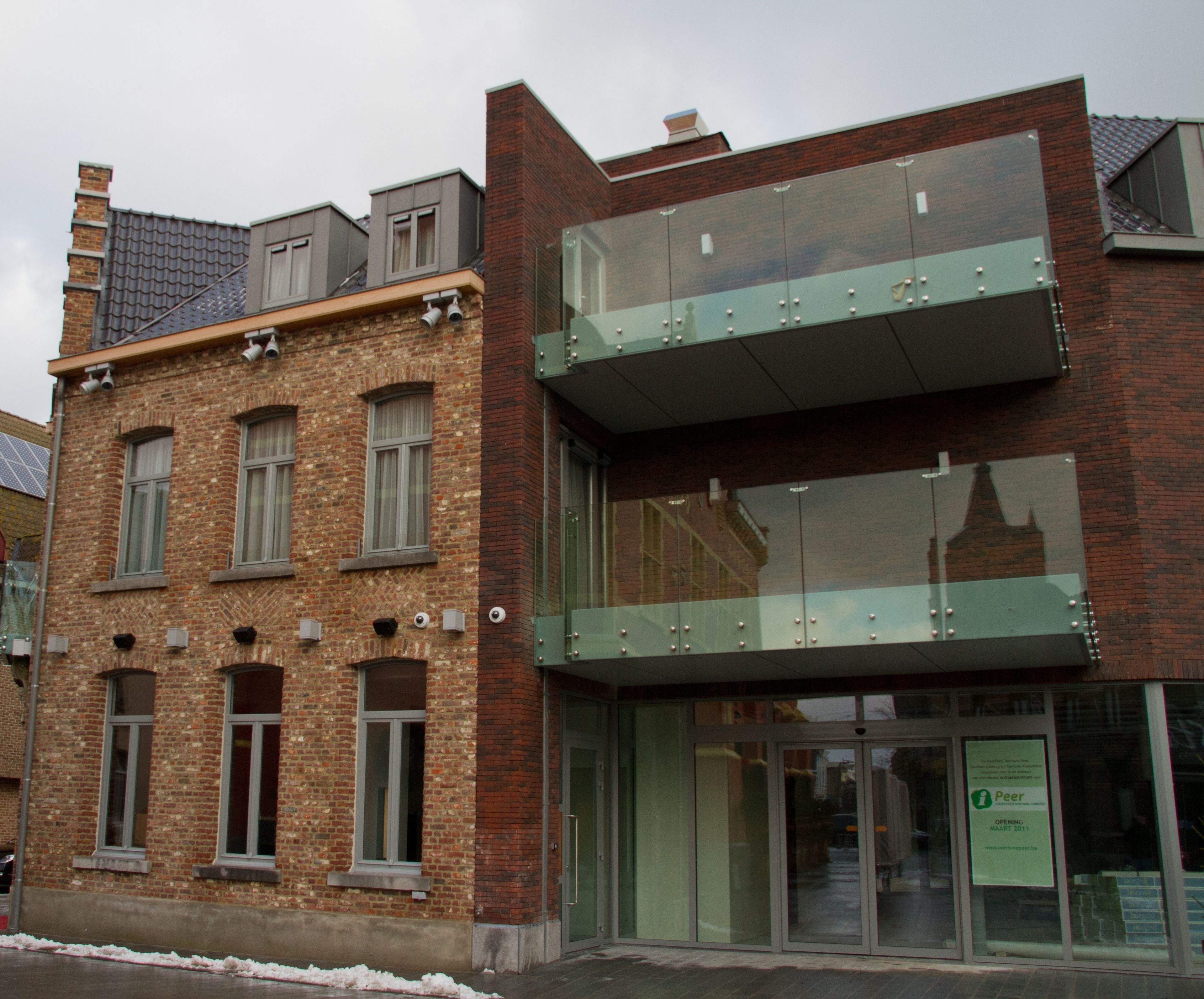 A modern building with a brick facade, large windows, and a glass entrance.