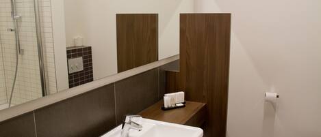 A bathroom with a white sink, a mirror, a toilet, and a shower area.