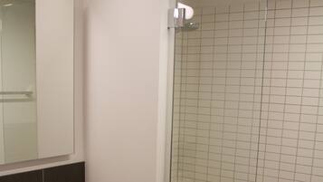 A modern bathroom with a white sink, mirror, and glass-enclosed shower.