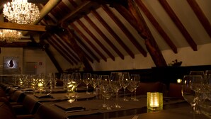 En svagt oplyst restaurant med flere spiseborde, en lysekrone og stearinlys.