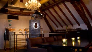 A dining area with a chandelier, a stone pillar, and a coat rack with hangers.