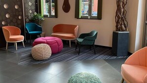 A modern interior with a seating area featuring multiple chairs and a large round ottoman. - Hotel De Boskar (Peer)